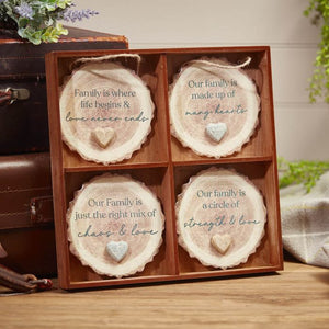 A Family Bark Hanger With Resin Pebble Heart with four sections, each containing a round resin pebble heart with a family-themed quote: "Family is where life begins & love never ends," "A family is made up of many hearts," "Our Family is just the right mix of chaos & love," and "Our family is a circle of strength & love." Bring warmth to your home decor.