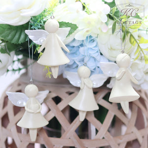 Four Large Hanging Angels with simple, smooth designs and small wings are hanging in front of a basket filled with various white, yellow, and blue artificial flowers. These charming angels, perfect for home decor, have different poses and are suspended on thin silver strings.