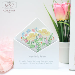 A Wooden Floral Envelope Flower Boxes with colorful floral card inserts is displayed with the words "Wonderful friend" and a friendship quote. Set against a backdrop of a pink tulip in a vase and pastel pink tissue paper, this charming piece of home decor features the brand "KC Cottage" in the top left corner.