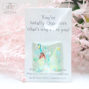 A small Pocket Hugs with Sentiments package with an illustration of a duck in a field of plants. The packaging reads, "You're totally Quackers (that's why I like you)." The Pocket Hugs with Sentiments card includes a note about the importance of keeping it at all times as a reminder of care. Ideal for adding charm to your home decor.
