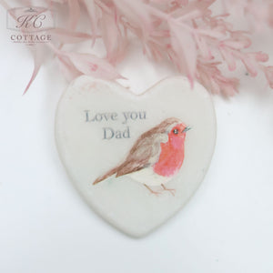 A Marble Pocket Pebble Robin Sentiment Heart featuring a watercolor-style robin bird design with the text "Love you Dad" above. The background includes soft pink flowers at the top, making it a charming piece of home decor.