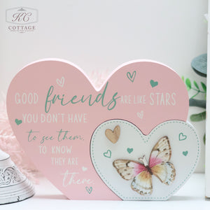 A decorative home decor display by KC Cottage features a larger pink heart with the text "Good friends are like stars. You don't have to see them to know they are there." Next to it is a smaller heart-shaped frame with a butterfly image inside, collectively known as Bright Butterfly Heart Plaques.