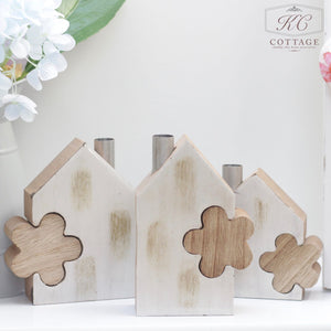 Three Wooden House Set with Flower Block are displayed against a white background. White and pink flowers partially frame the left side of the image, creating a charming home decor scene.