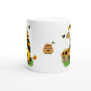 A white Bee & Sunflower Gonk Mug decorated with illustrated bees, honeycombs, sunflowers, and a honey jar labeled "Bee Happy." The design shows bees flying around the flowers and honeycombs, giving the mug a cheerful and lively look. This charming piece is perfect for adding a touch of whimsy to your home decor.