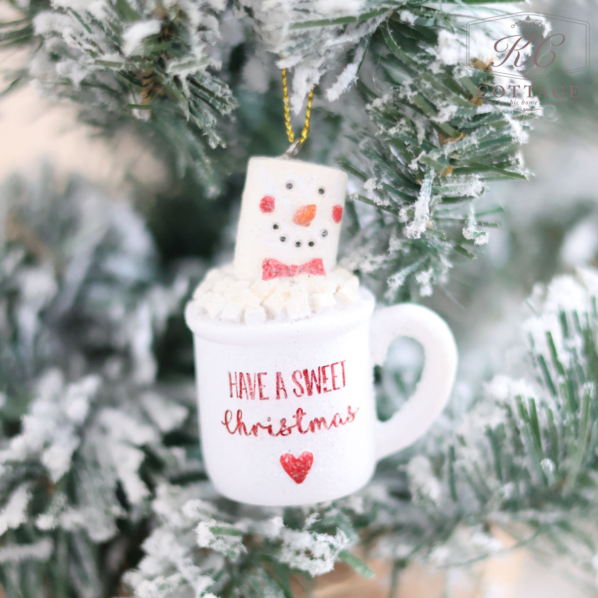 The Christmas Gingerbread & Mug Hanging Tree Ornament showcases a marshmallow snowman nestled inside, adorned with the phrase "Have a Sweet Christmas" and a cute red heart. This charming ornament hangs beautifully on a frosty evergreen branch, embodying the festive spirit of Christmas decorations splendidly.