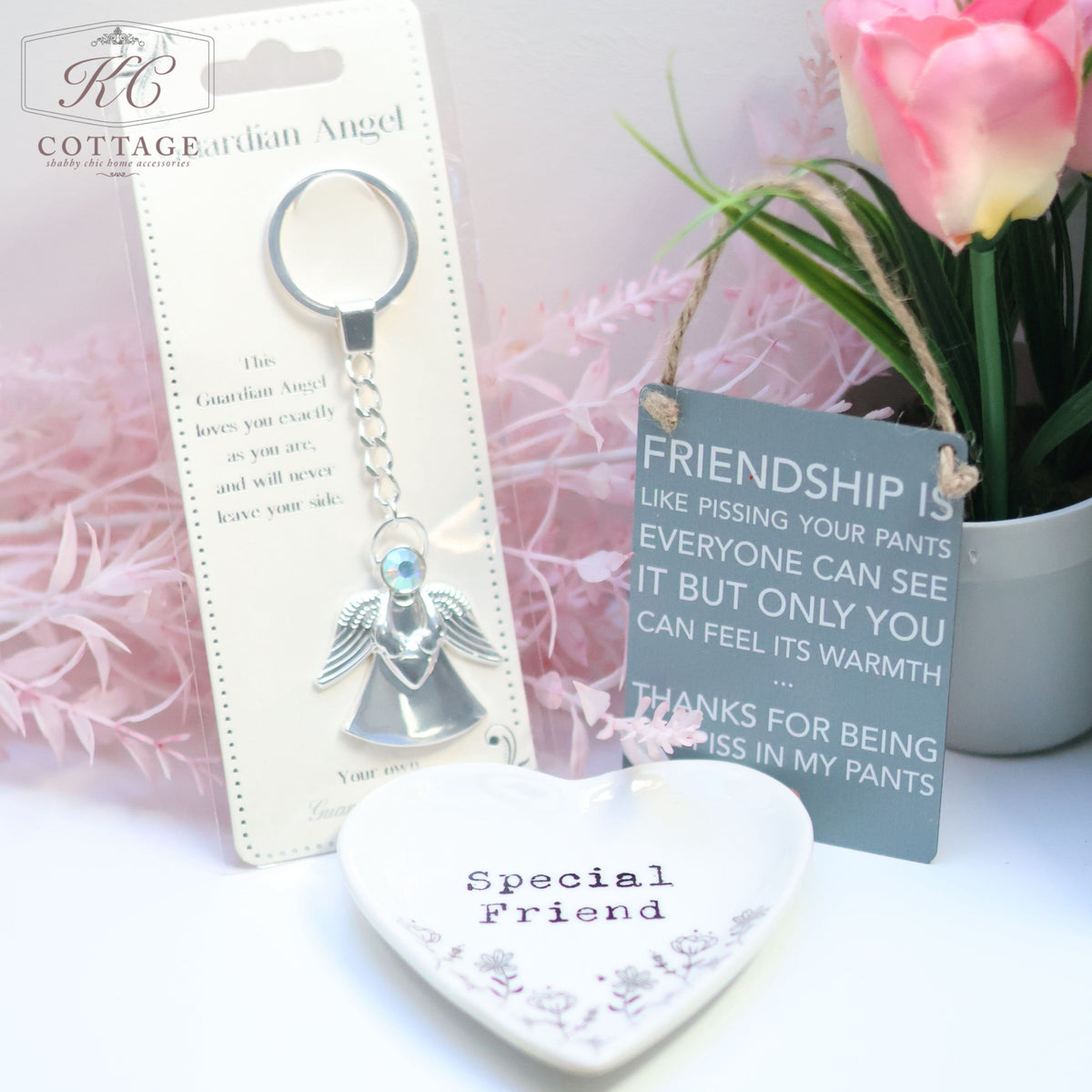 A close-up of the Gift Set - Best Friend featuring an angel keychain, a heart-shaped dish labeled "Special Friend," and a sign. The sign reads, "Friendship is like pissing your pants; everyone can see it but only you feel its warmth. Thanks for being the piss in my pants." This set adds charm to your home decor.