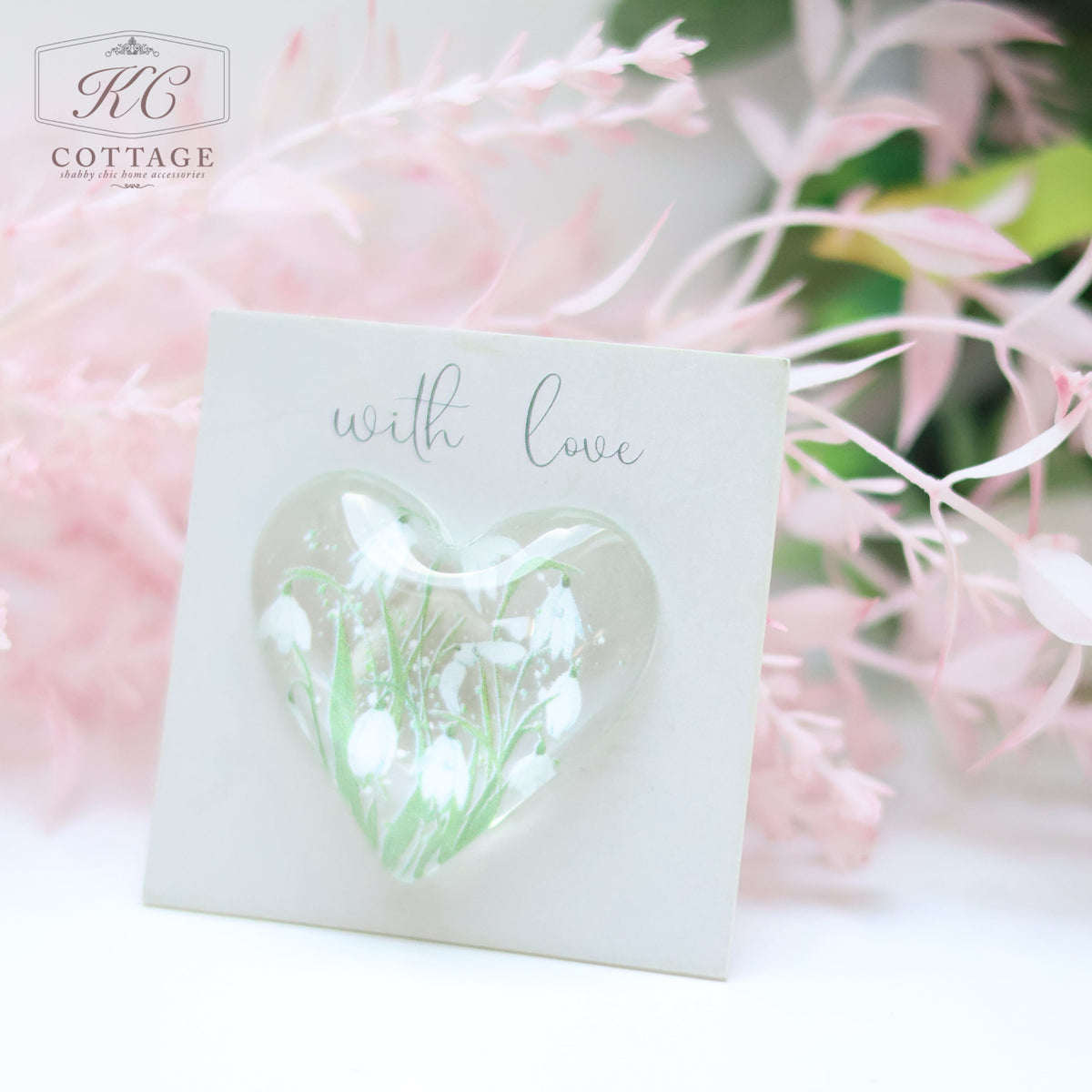 A Glass Spring Floral Heart with Sentiment Card is displayed against a soft pink background with foliage. The words "with love" are written above the heart, making it a charming piece of home decor.