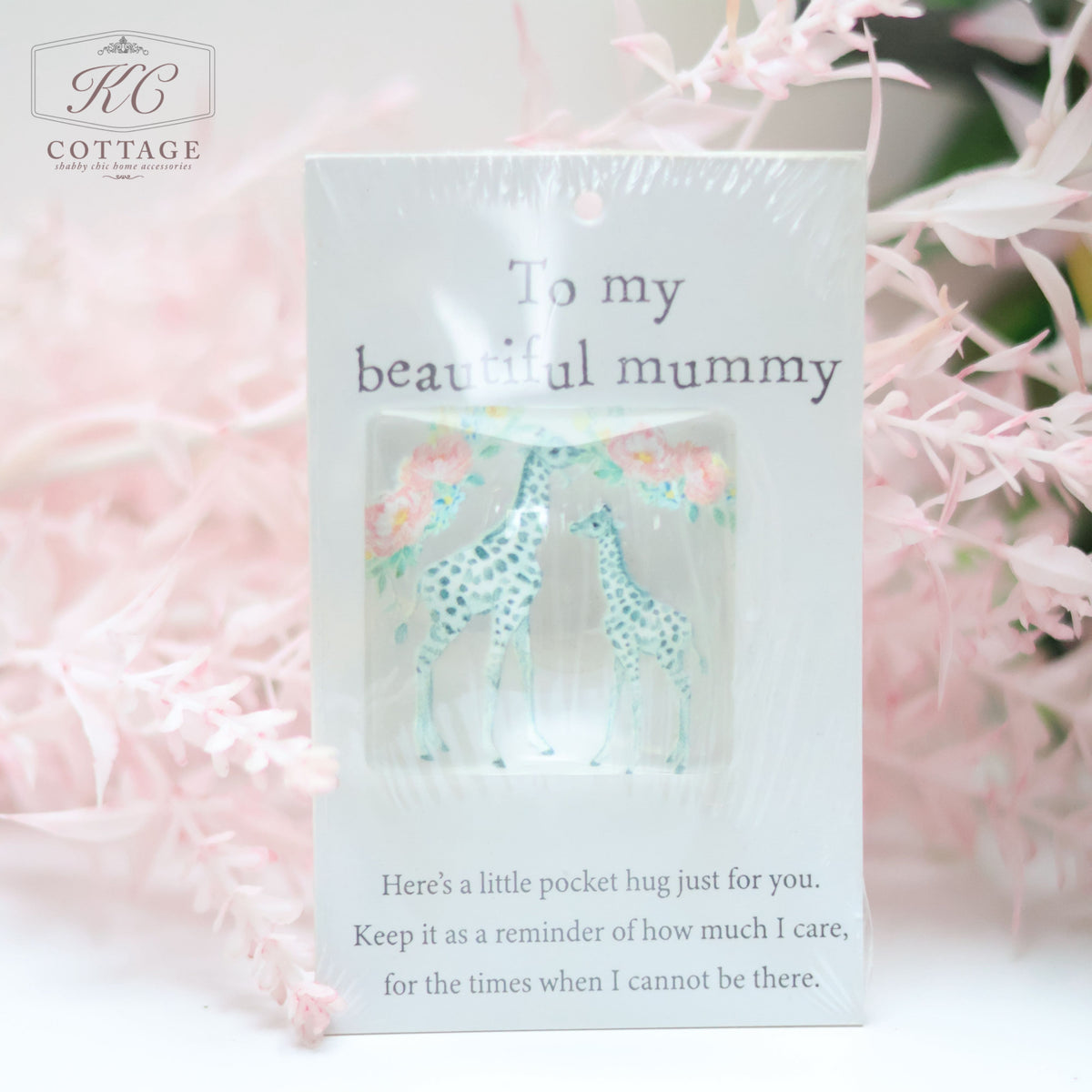 A Pocket Hugs with Sentiments card with "To my beautiful mummy" printed on it, featuring an illustration of two giraffes and a sentiment: "Here's a little pocket hug just for you. Keep it as a reminder of how much I care, for the times when I cannot be there." The pink floral background makes it perfect for home decor.