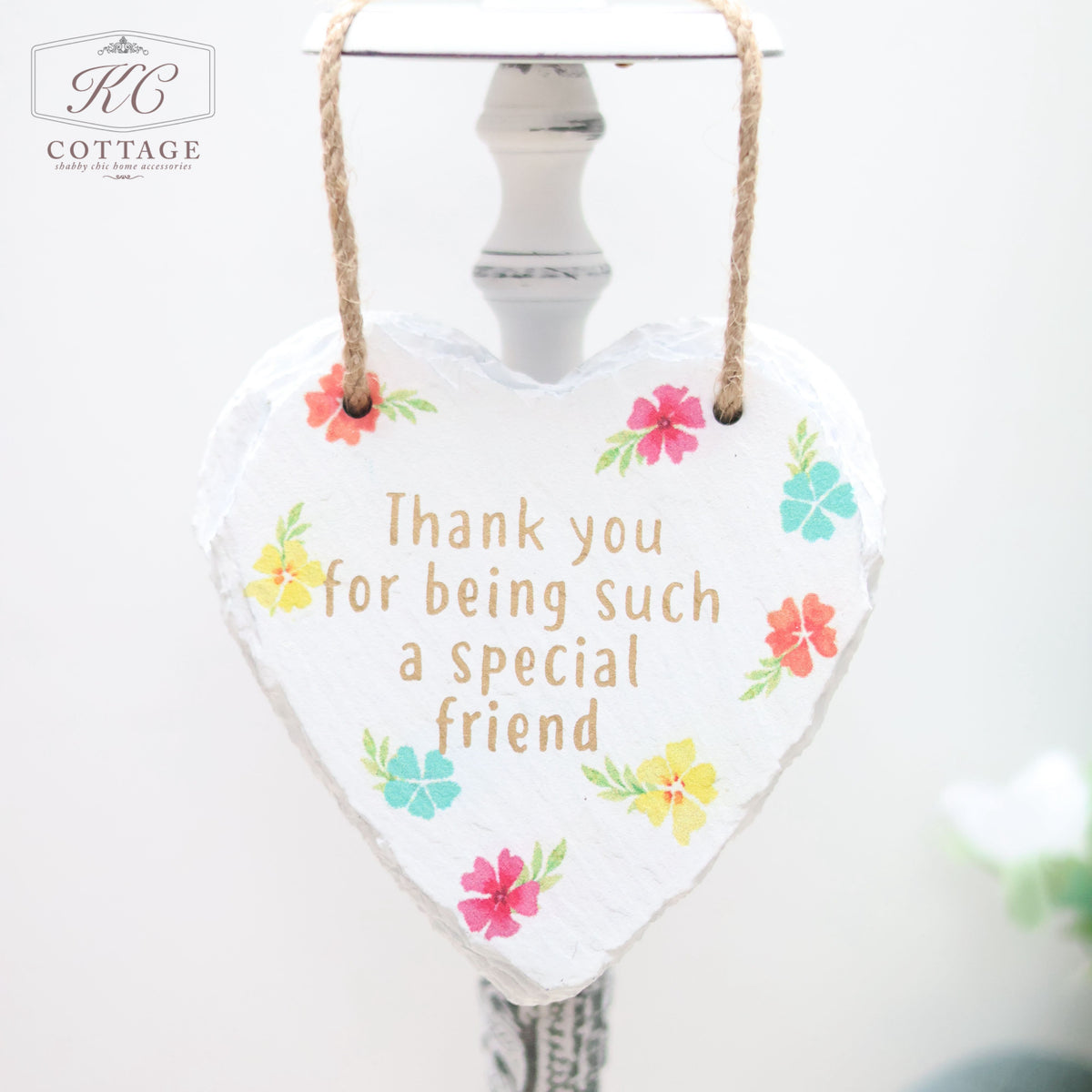 A **Bright Floral Slate Hanging Hearts** hanging from a rope, featuring colorful flowers and the message "Thank you for being such a special friend" written in the center. Perfect for home decor, this sign has a white background with a subtle floral design.