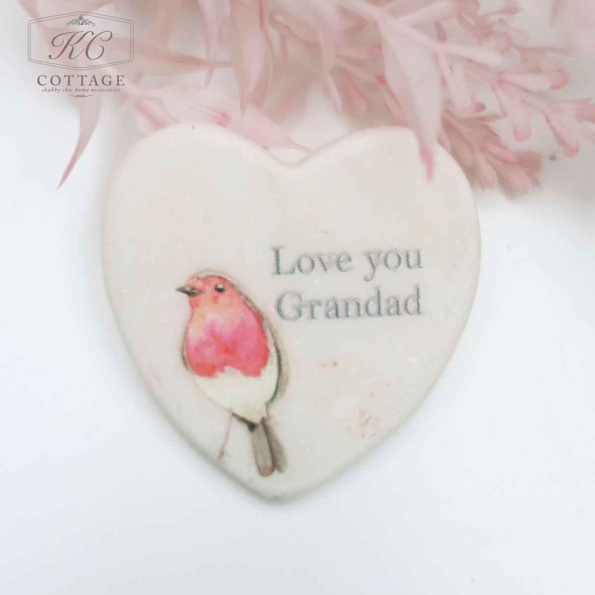 A Marble Pocket Pebble Robin Sentiment Heart features an illustration of a small bird and the words "Love you Grandad." Set against a backdrop of soft pink flowers, this piece adds a sentimental touch to home decor.