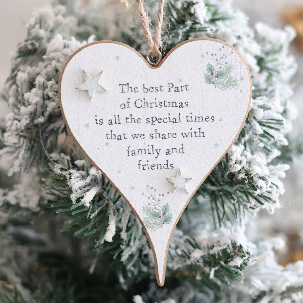 A Christmas Sentiment Heart Hanger With 3D Star, featuring decorative 3D stars and a pine branch, hangs on a snow-covered Christmas tree. The ornament displays the message: "The best part of Christmas is all the special times that we share with family and friends.