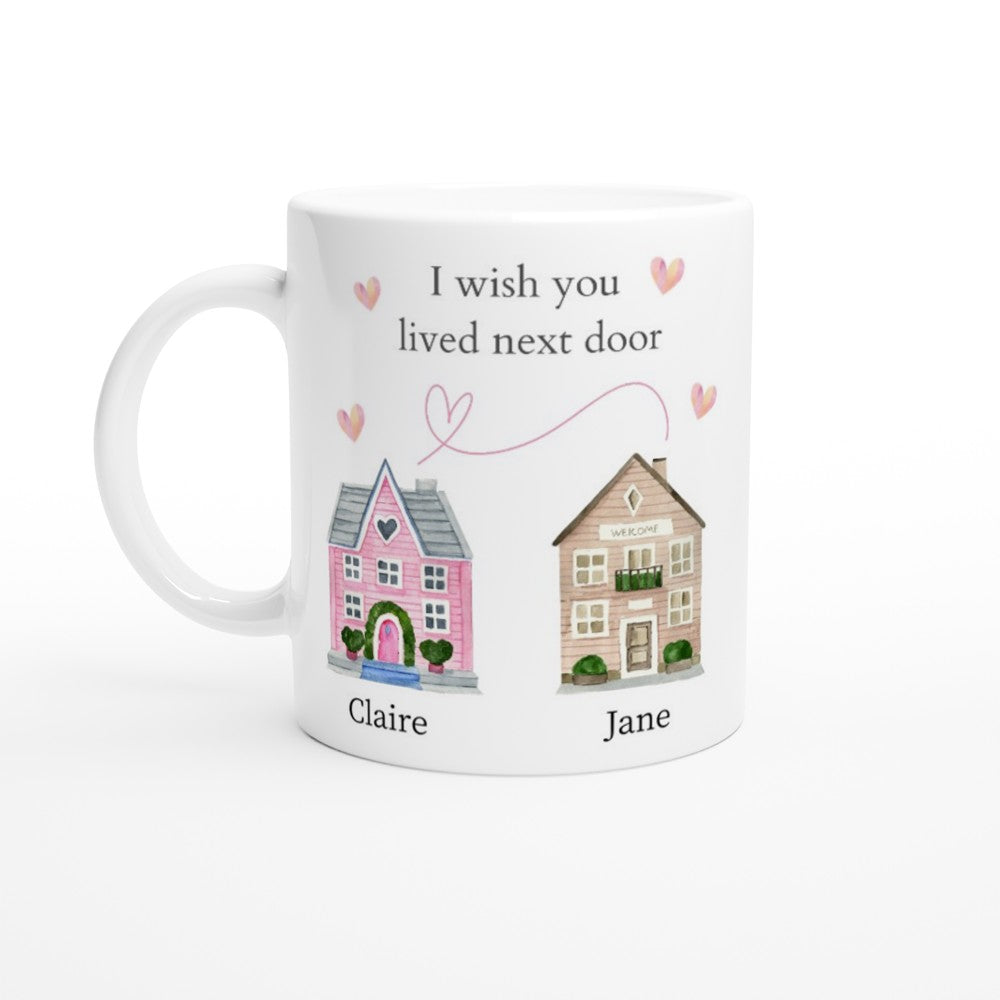 A white ceramic "I Wish You Lived Next Door Personalised Mug" featuring two illustrated houses labeled "Claire" and "Jane." The houses are connected by a dashed line with hearts, and the text above reads, "I wish you lived next door." This charming piece of home decor makes a heartfelt gift.