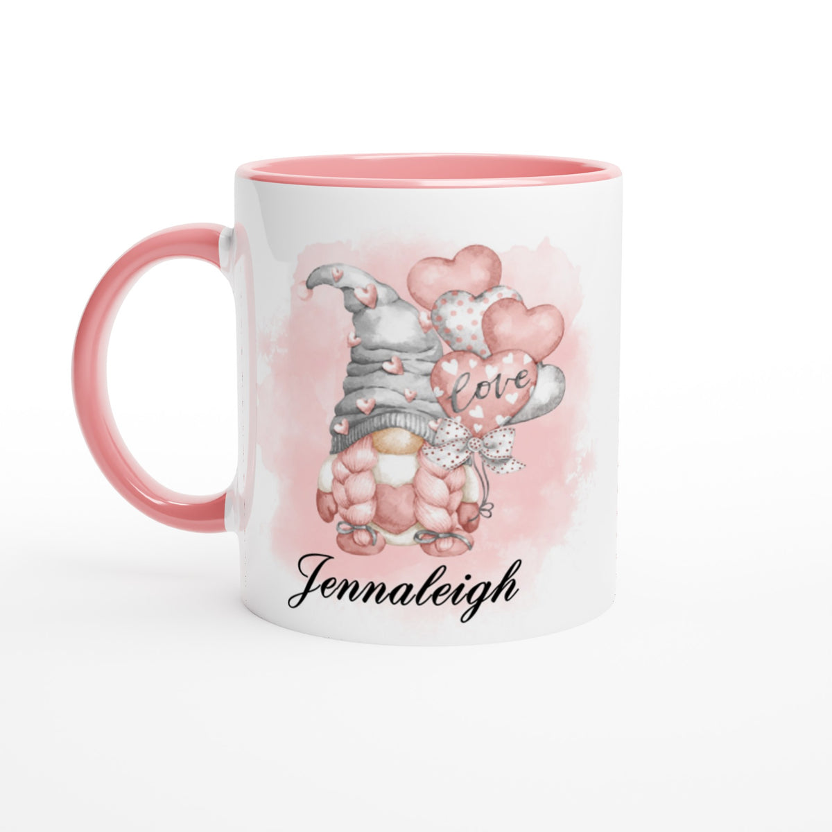 A white ceramic mug with a pink handle and interior features a cute gnome holding heart-shaped balloons. The word "love" is written on one balloon, and the name "Jennaleigh" is printed at the bottom. The background has a light pink watercolor effect, making the Personalised Pink Love Gonk Mug a charming piece of home decor.