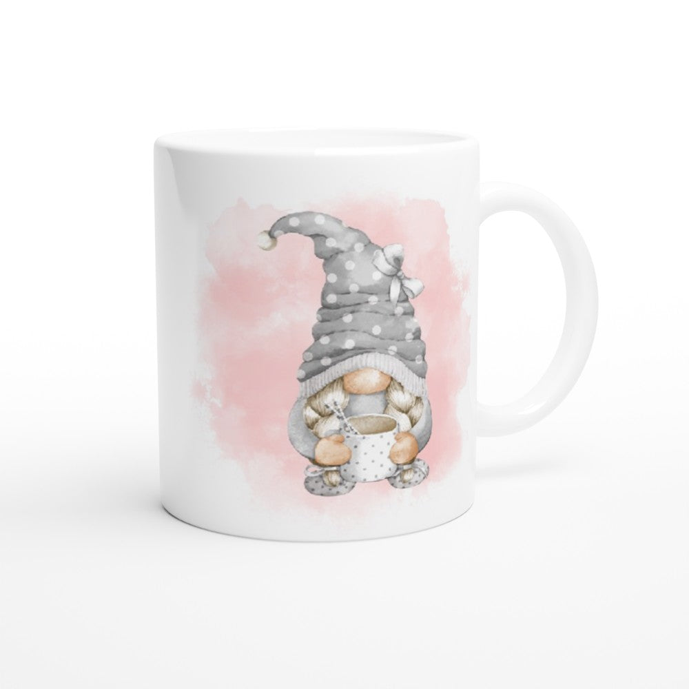 A Pink and Grey Gonk Mug featuring a cute illustration of a gnome with a gray polka-dotted hat holding a cup. The background has a soft pink watercolor-like splash, making it a charming addition to your home decor.