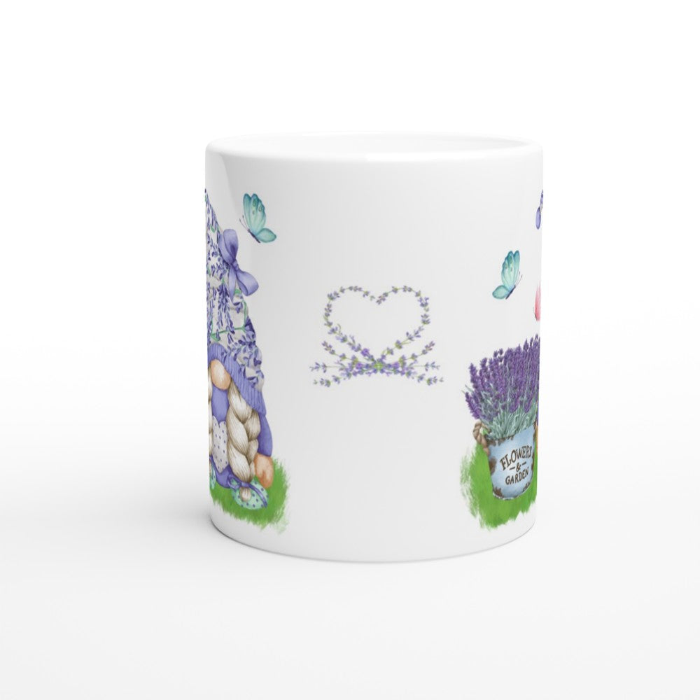 A Gonk Lavender & Butterfly Mug featuring a charming floral illustration that adds to your home decor. The design includes a basket of lavender, butterflies, a heart-shaped wreath made of flowers, and a garden scene with various blooming plants. The plain white handle complements the whimsical artwork.