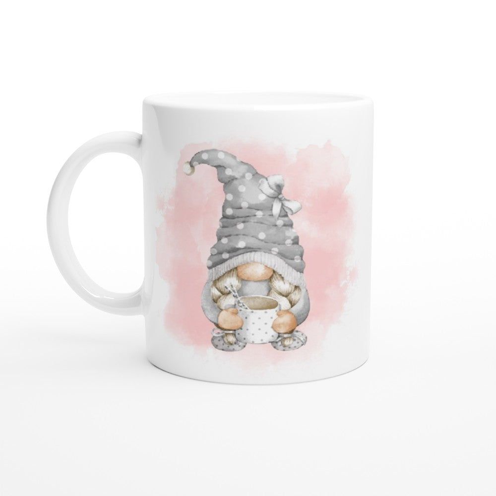 This Pink and Grey Gonk Mug, perfect for home decor, features a cute illustration of a gnome with a gray polka-dotted hat, wearing glasses, and holding a polka-dotted teacup. The background behind the gnome showcases a pink watercolor effect.